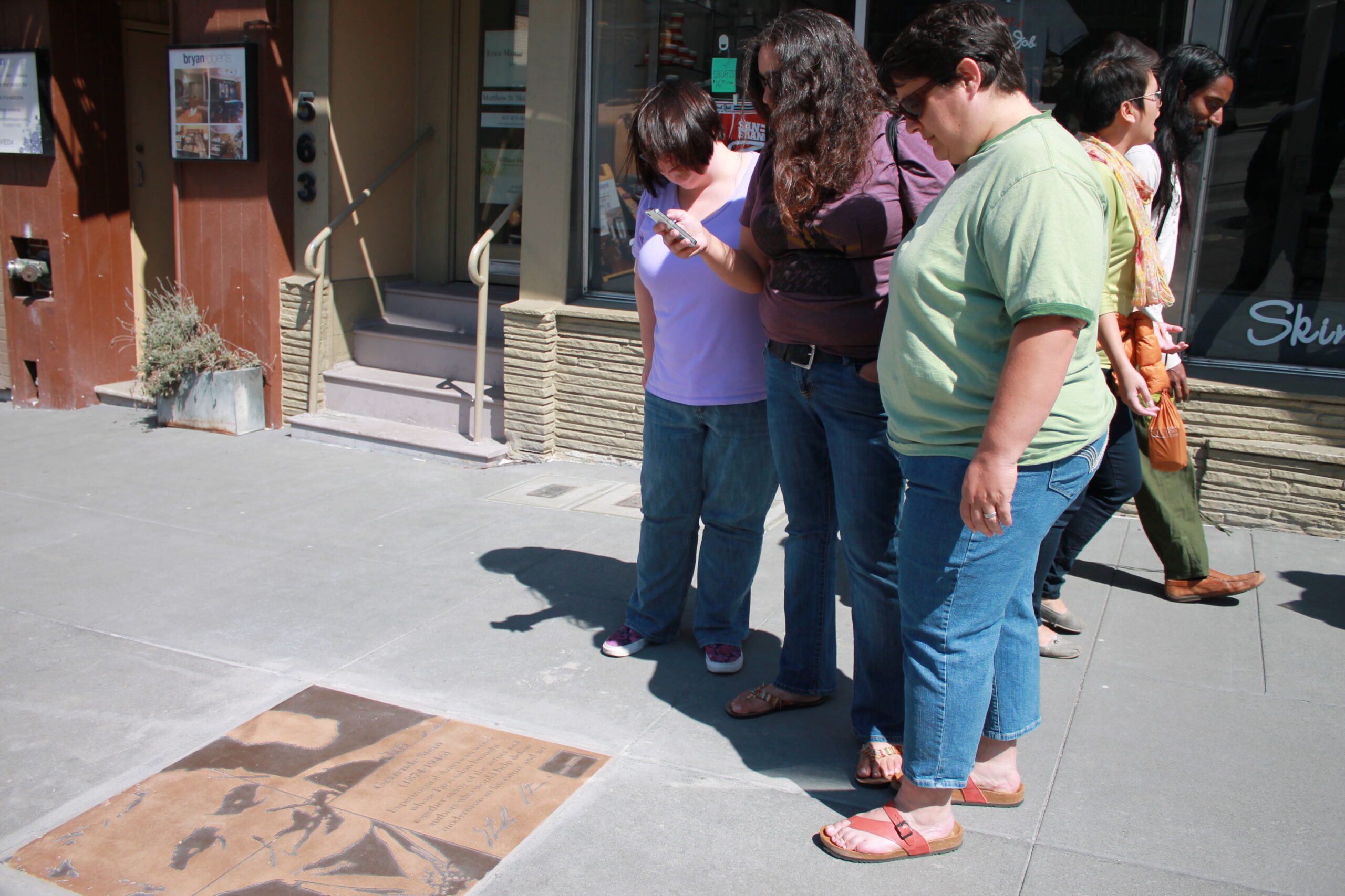 Former San Francisco Assistant District Attorney Rebecca Prozan, foreground, her wife, attorney Julia Adams, background, and their friend, center, pause to read the plaque honoring American lesbian writer Gertrude Stein outside of Hand Job Nails and Spa on Castro Street near 19th Street. (Photo: Heather Cassell)