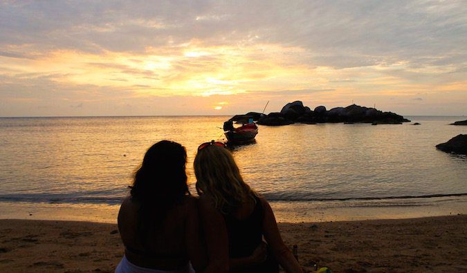 Lesbian couple watching sunset on a beach