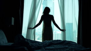 Woman looks out hotel room window