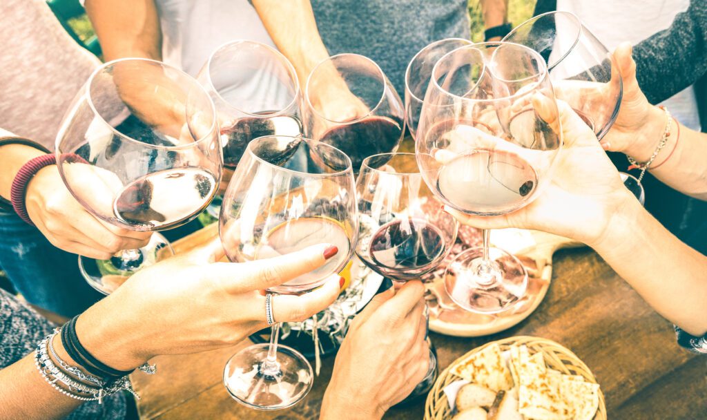 Friends toasting red wine during a wine tasting at a countryside farmhouse vineyard.