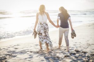 Lesbian-Couple-Walking-Deserted-Beach-AdobeStock-loreanto